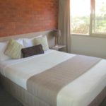 A bed room with a neatly made bed and a window