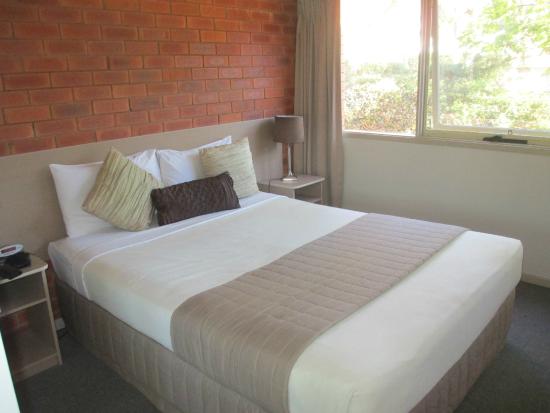 A bed room with a neatly made bed and a window