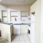 A kitchen with white cabinets and tiled floors.