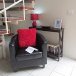 63758098 A black chair with red pillow and book on the arm.