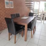 A dining room table with six chairs and a brick wall.